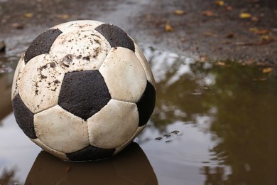 Photo of Dirty soccer ball in muddy puddle, space for text