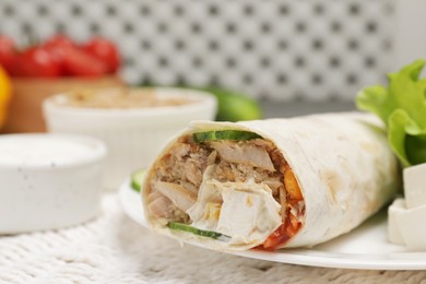Photo of Delicious tortilla wrap with tuna on white wicker mat, closeup. Space for text