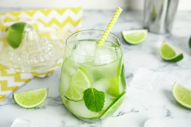 Photo of Delicious mojito and ingredients on white marble table