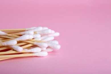 Photo of Wooden cotton buds on pink background, closeup. Space for text