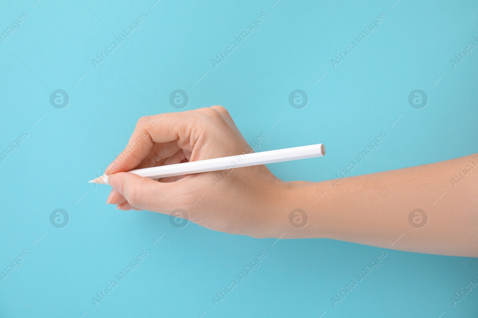 Photo of Woman with white pencil on light blue background, closeup