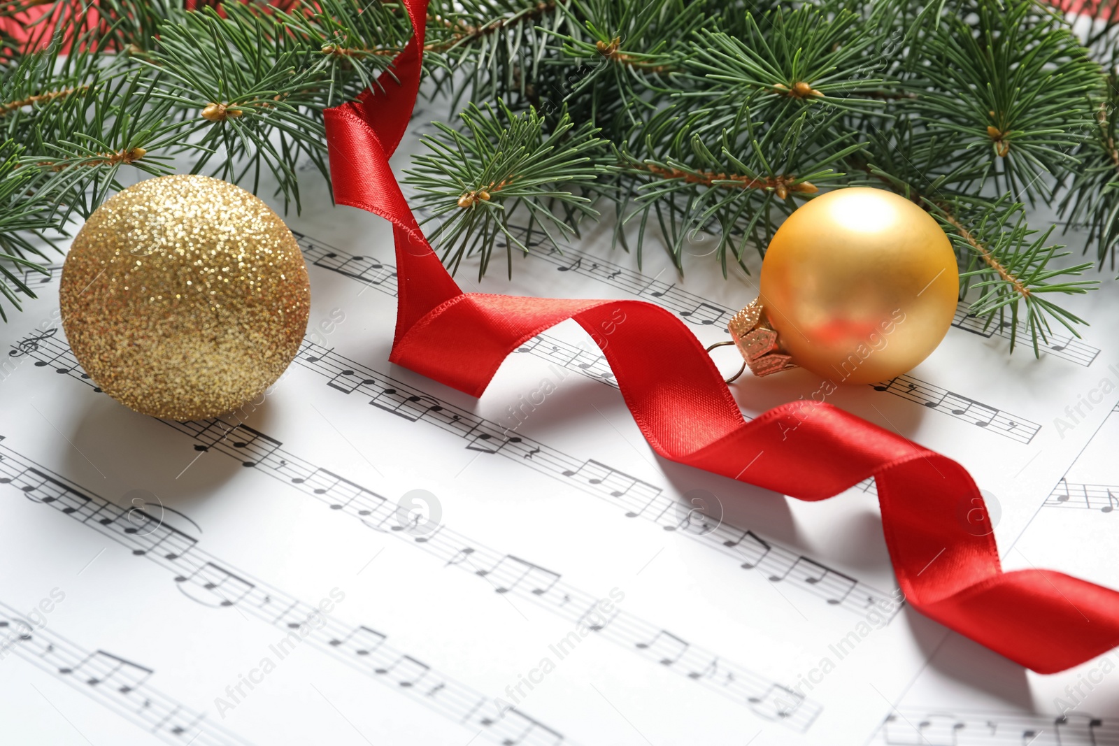 Photo of Fir tree branches with Christmas balls and ribbon on music sheets