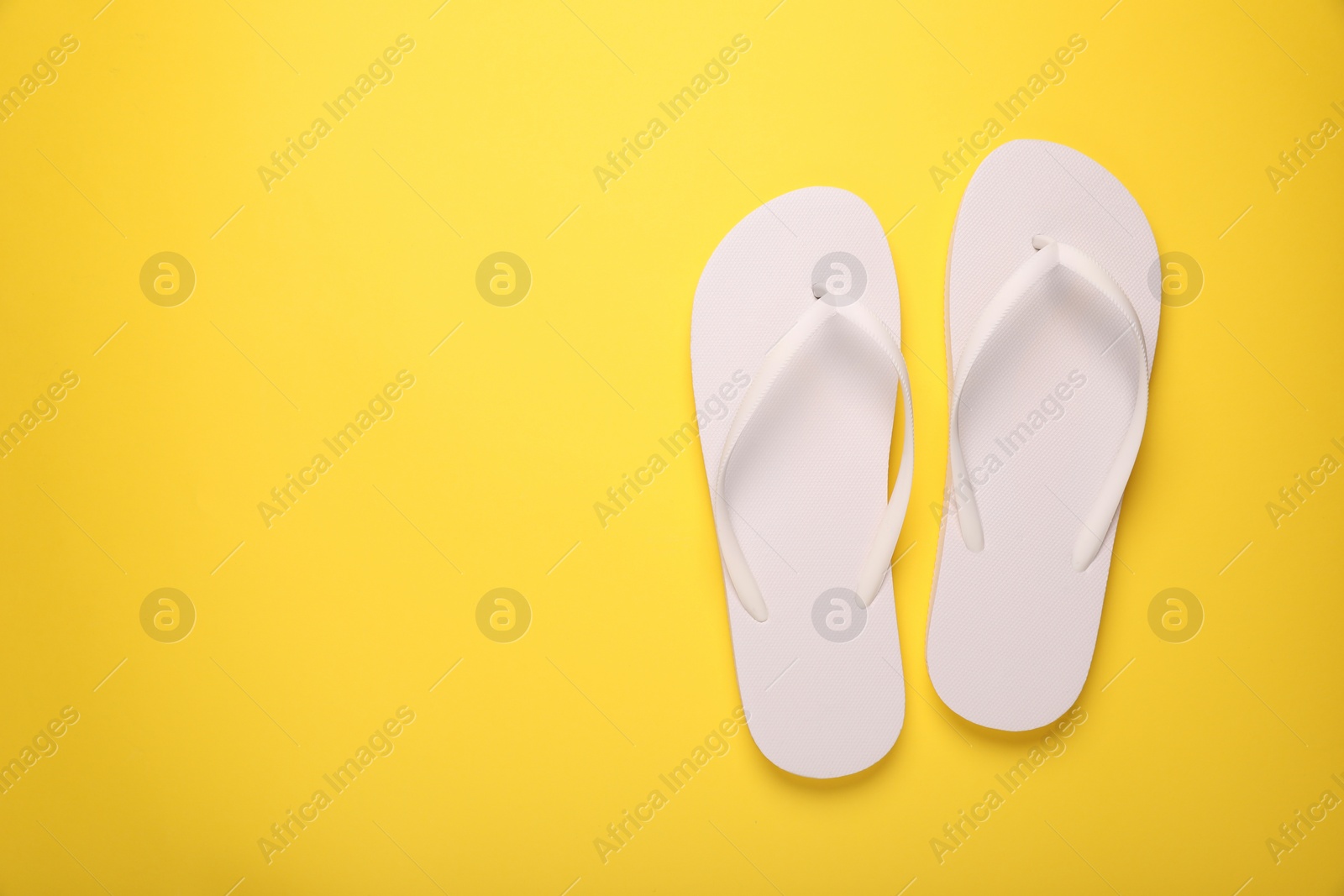 Photo of Stylish flip flops on yellow background, top view. Space for text