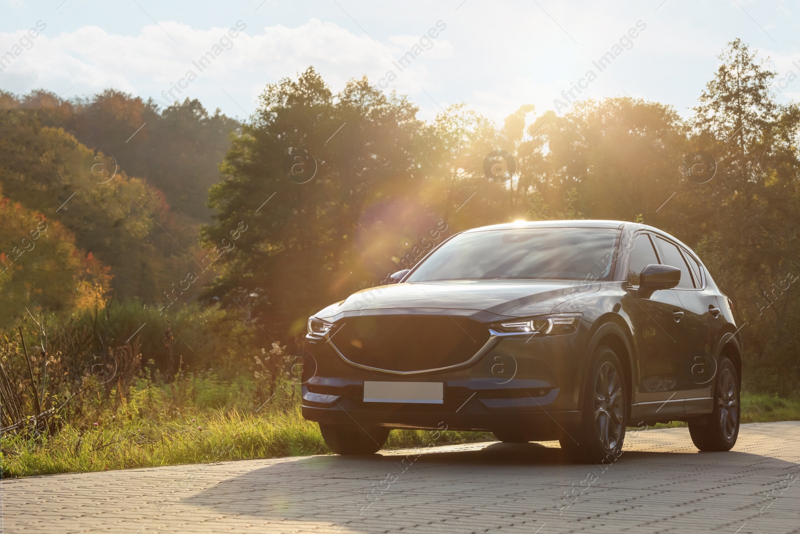 Photo of Black modern car on paved road at sunset, space for text