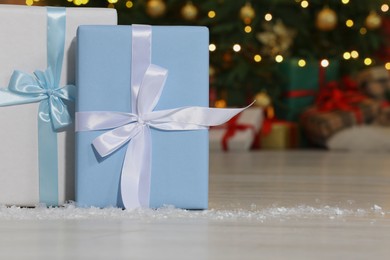 Gift boxes on floor near Christmas tree in room, space for text