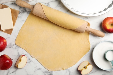 Dough for traditional English apple pie and ingredients at white marble table, flat lay