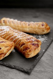 Photo of Fresh tasty puff pastry with sugar powder on grey table, closeup
