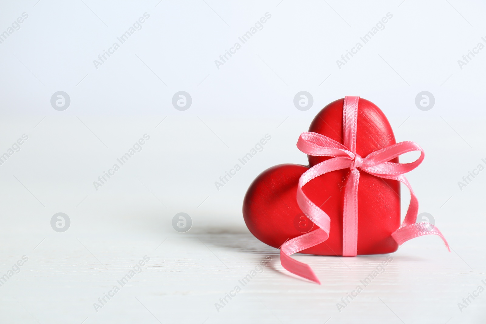 Photo of Red decorative heart with ribbon and bow knot on table. Space for text