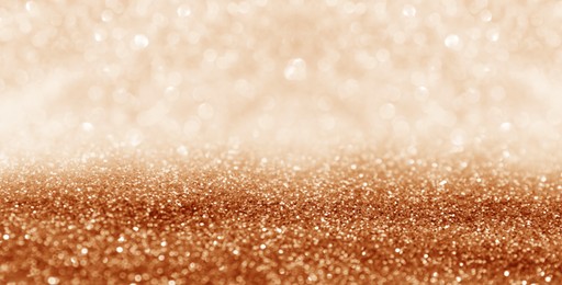 Shiny orange glitter and blurred lights on background, banner design. Bokeh effect