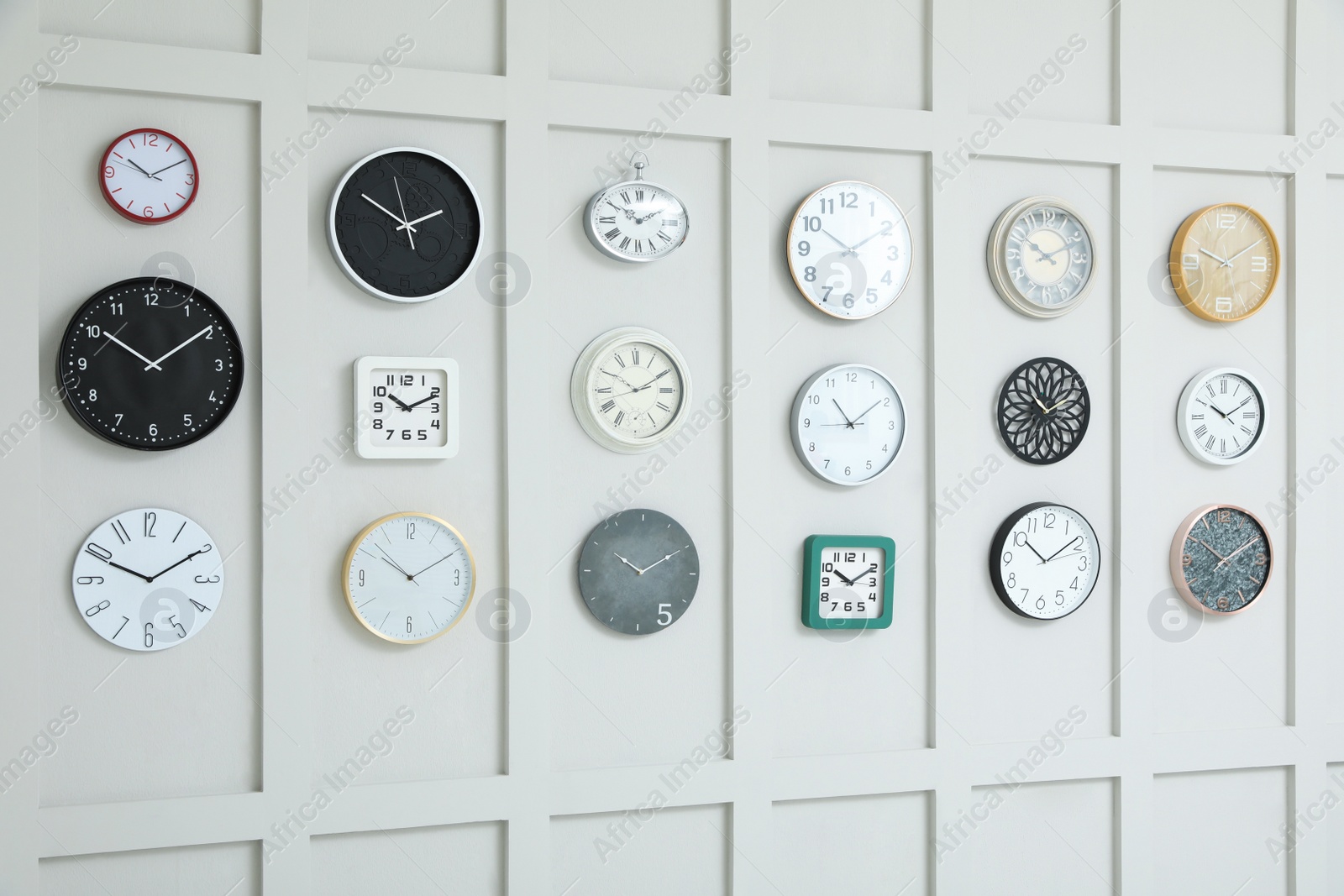 Photo of Many different clocks hanging on white wall.