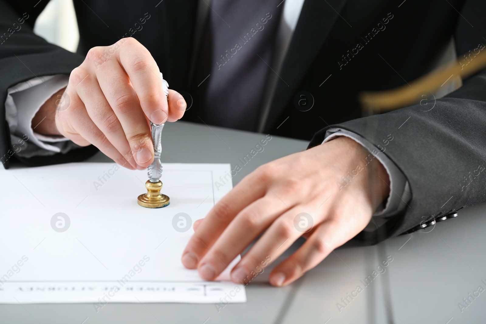 Photo of Male notary stamping document at table, closeup