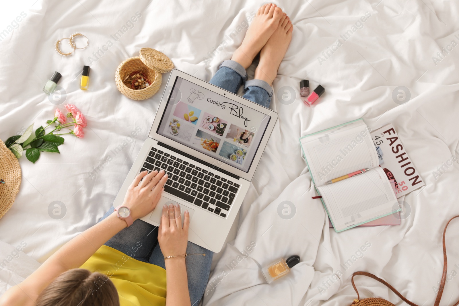 Photo of Woman and laptop with open cooking blog on bed, top view