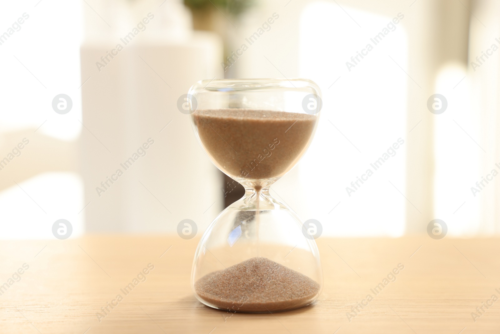 Photo of Sandglass on wooden table indoors, closeup. Spa time