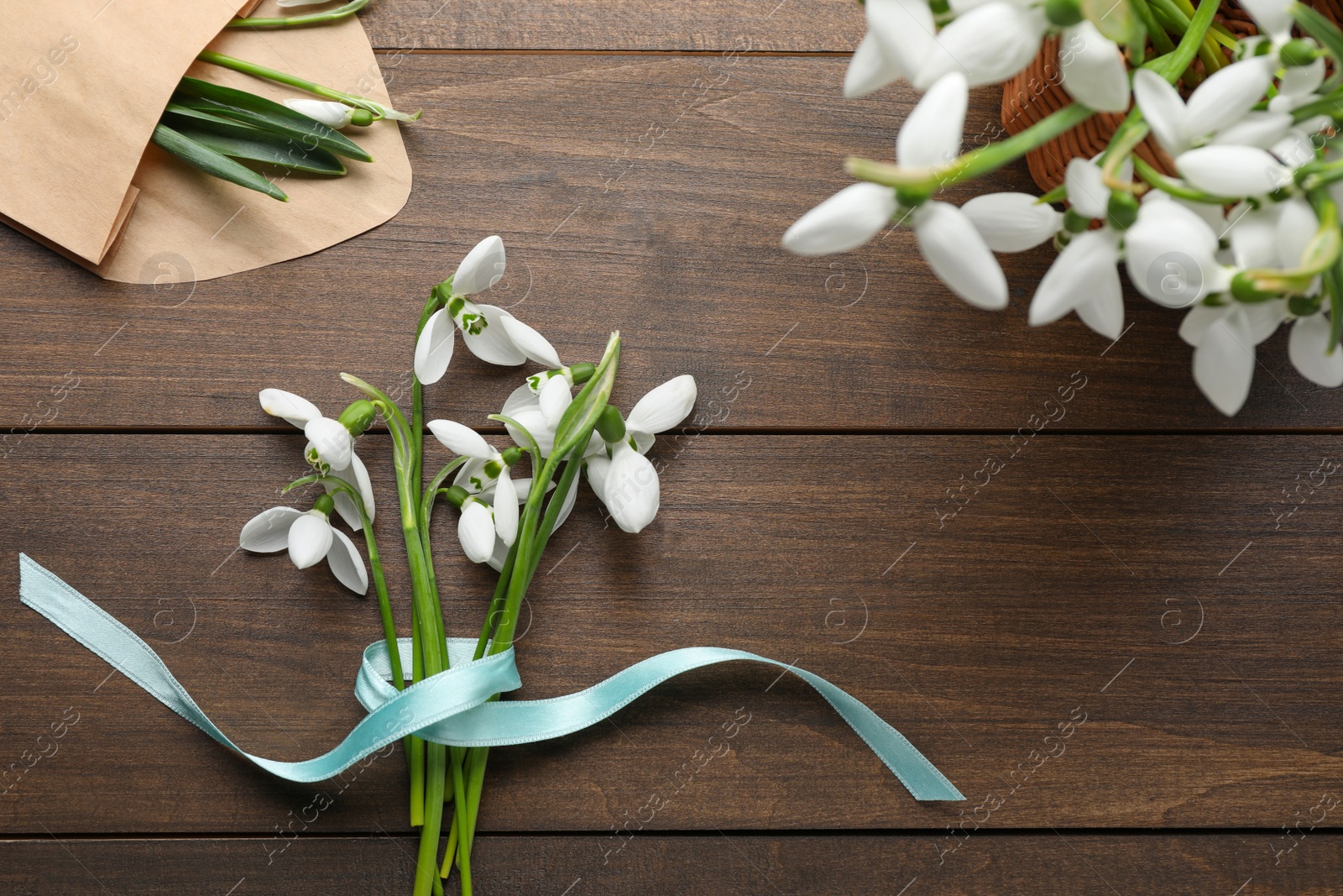 Photo of Beautiful snowdrops on wooden table, flat lay