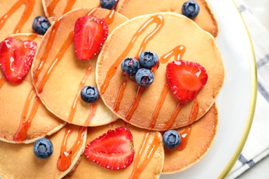 Photo of Delicious pancakes with fresh berries and syrup on table, closeup