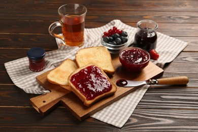 Delicious toasts served with jam, tea and berries on wooden table