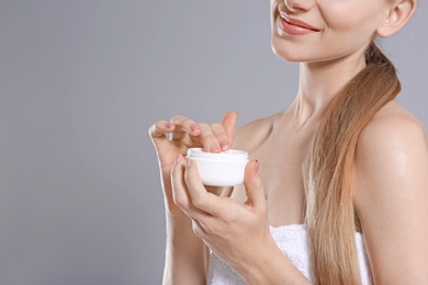 Young woman with jar of body cream on color background