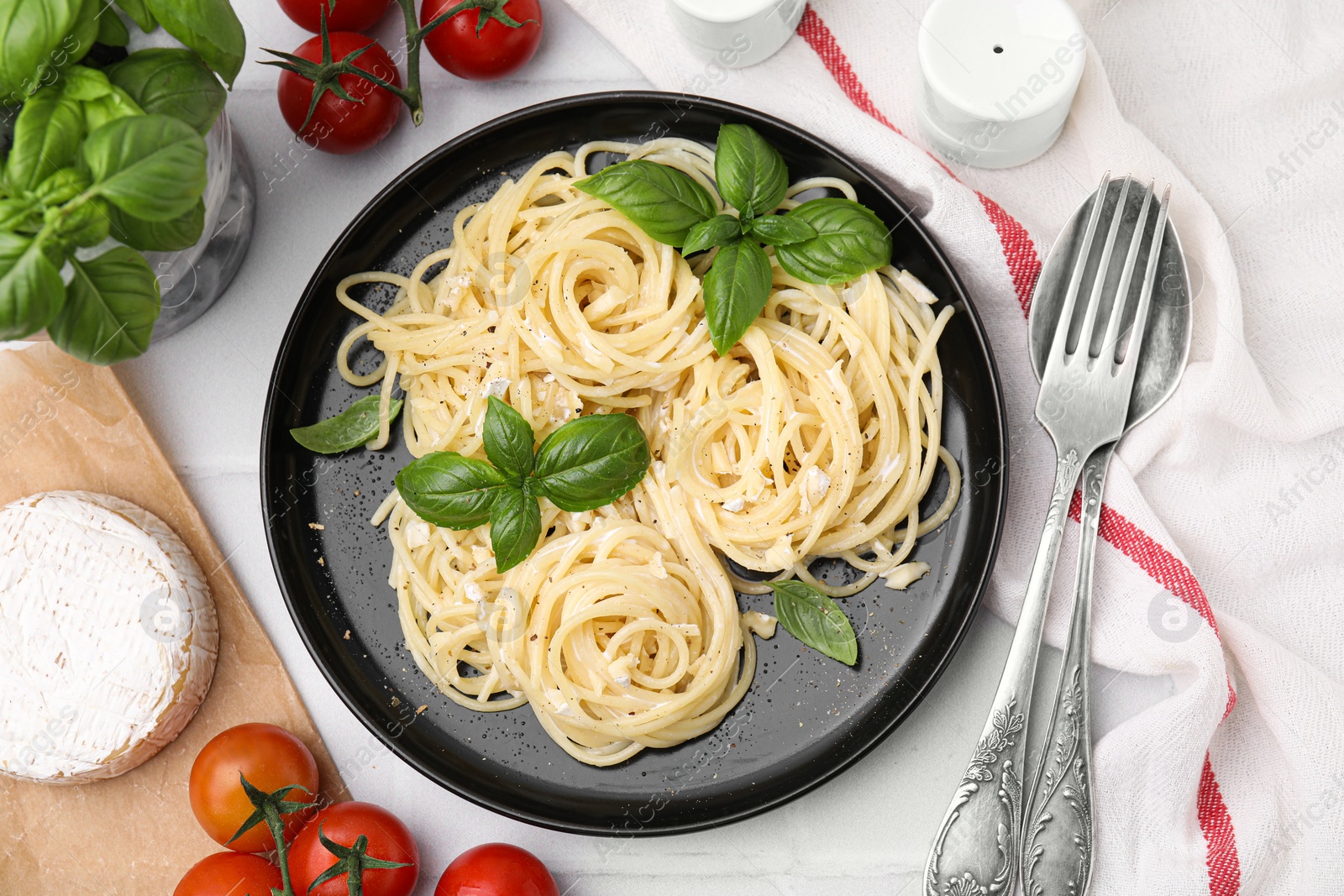 Photo of Delicious pasta with brie cheese and products served on white tiled table, flat lay