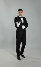 Handsome butler with tray on light grey background