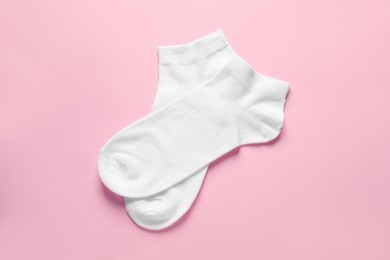 Photo of Pair of white socks on pink background, flat lay