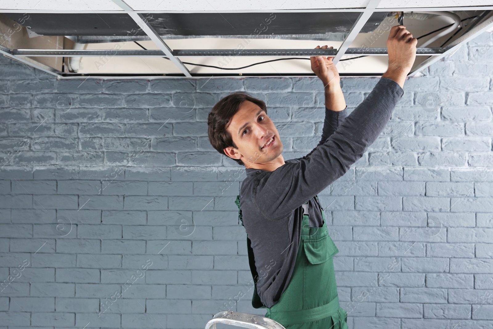 Photo of Young male technician repairing air conditioner indoors