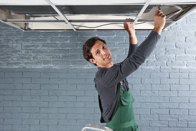 Young male technician repairing air conditioner indoors