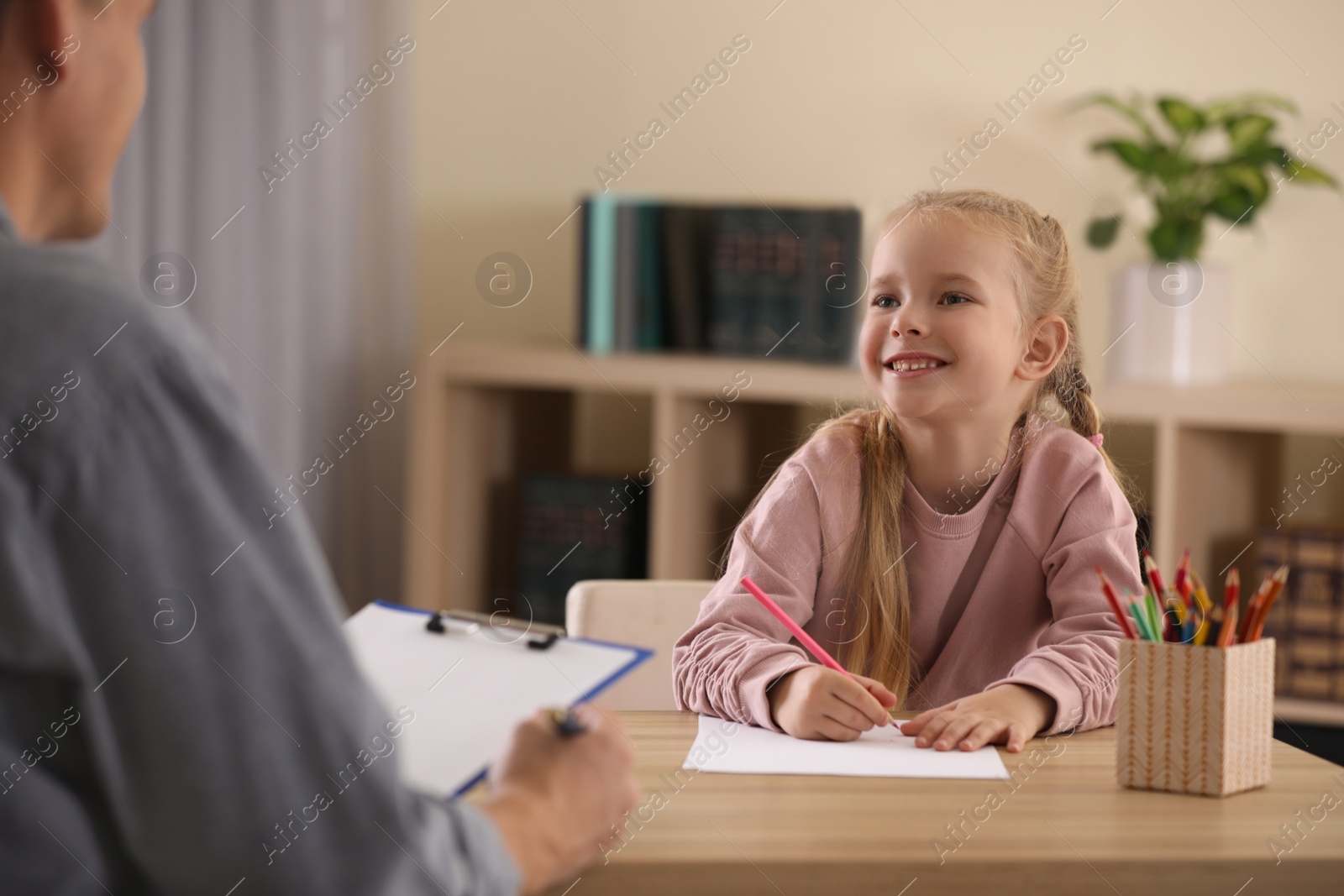 Photo of Little girl on appointment with child psychotherapist indoors