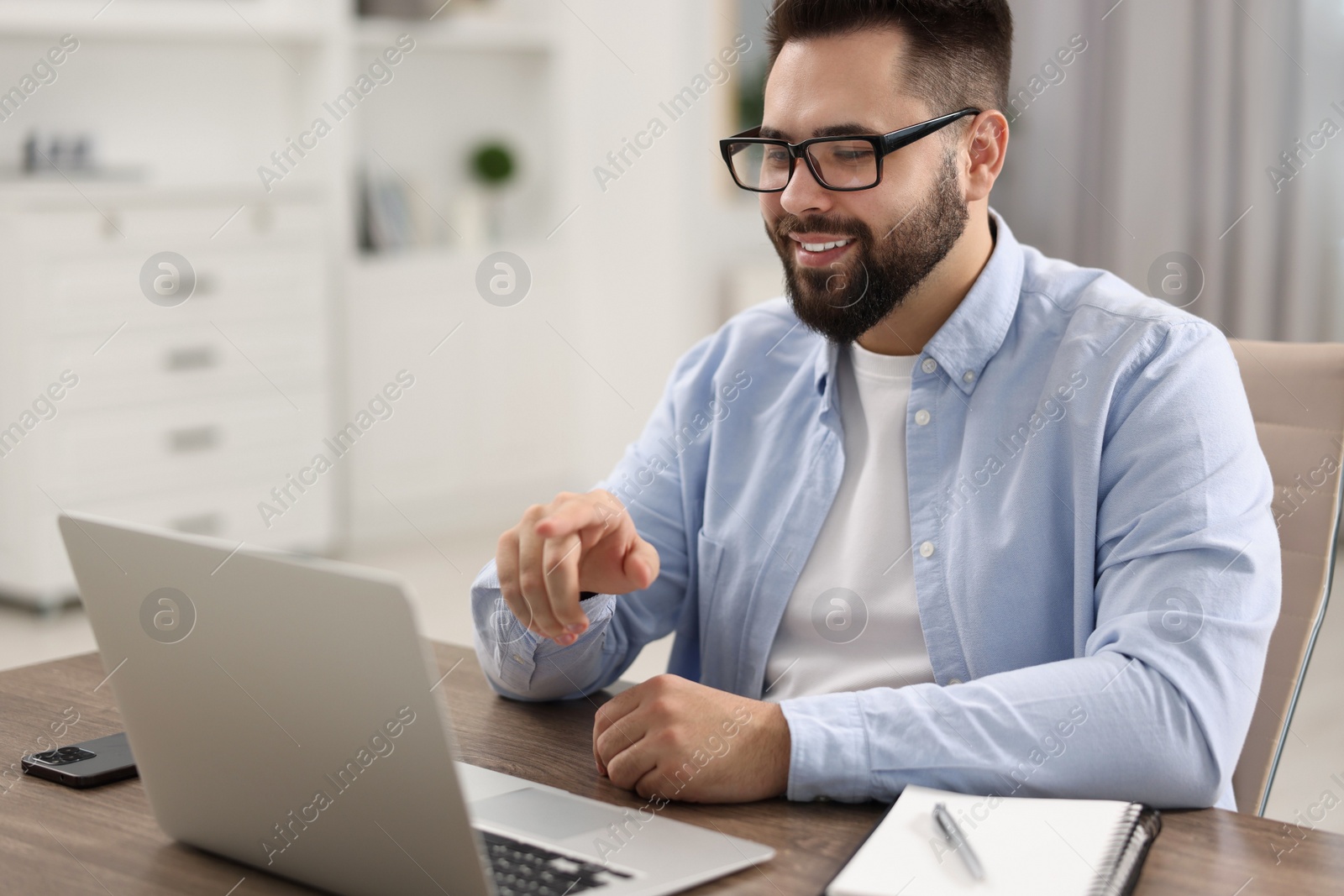 Photo of Young man using video chat during webinar at table in room