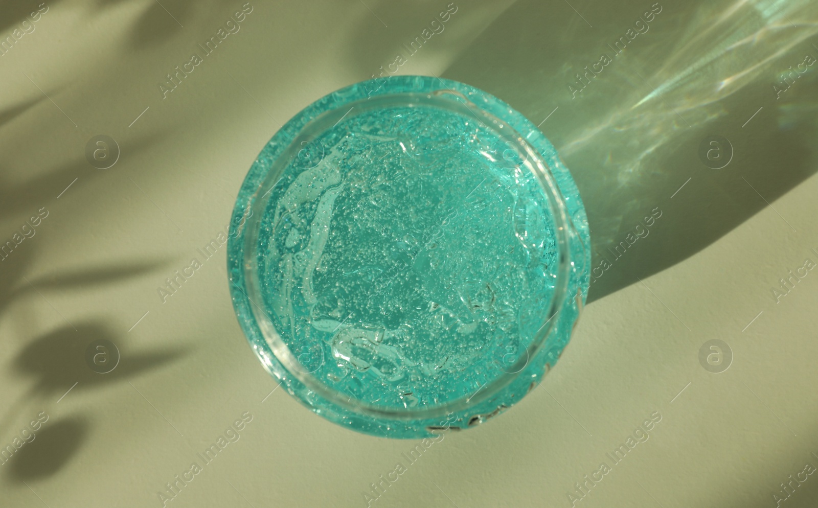 Photo of Jar of blue cosmetic gel on light table, top view