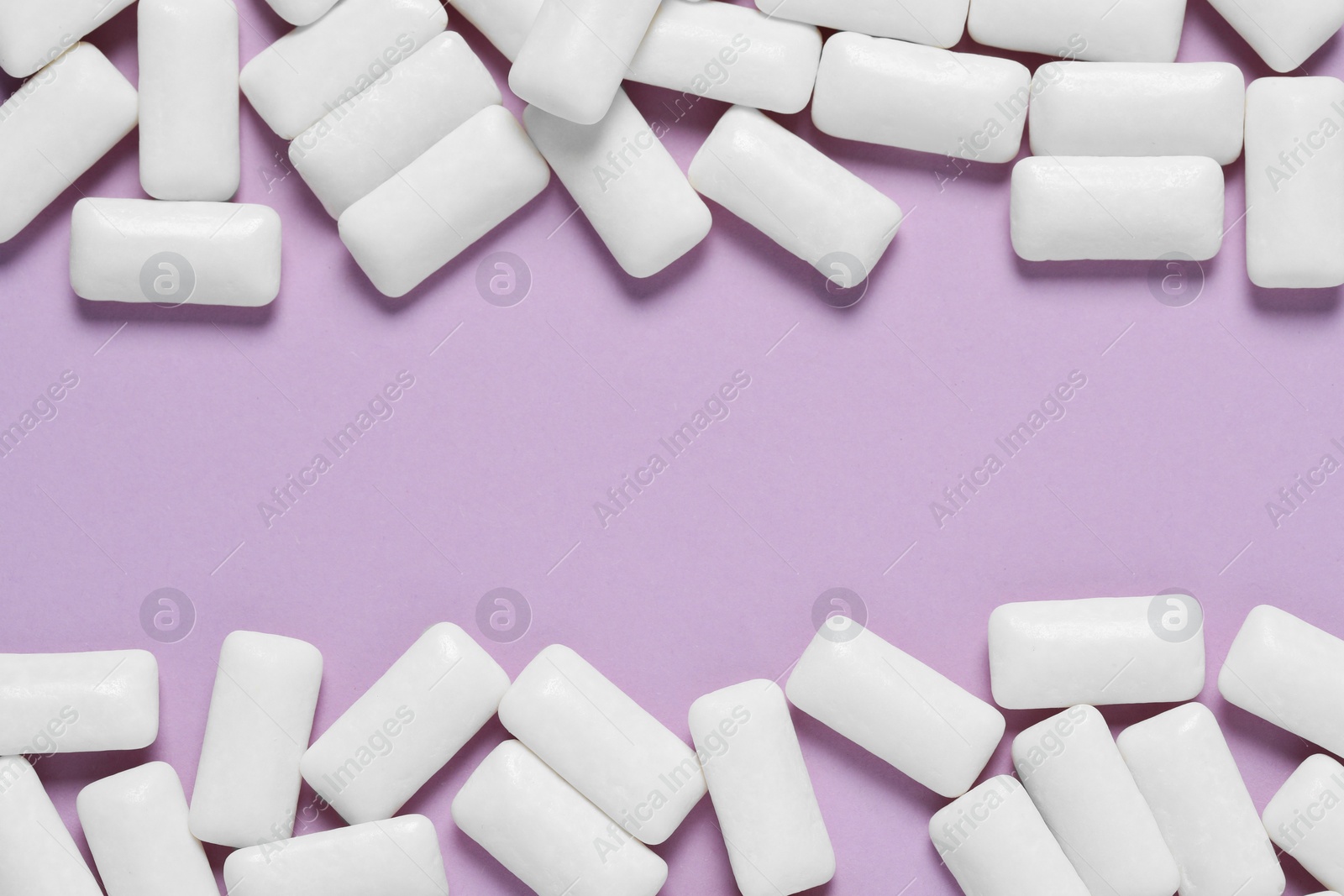 Photo of Frame made of white chewing gums on lilac background, flat lay. Space for text