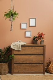 Photo of Wooden chest of drawers near brown wall at home. Interior design