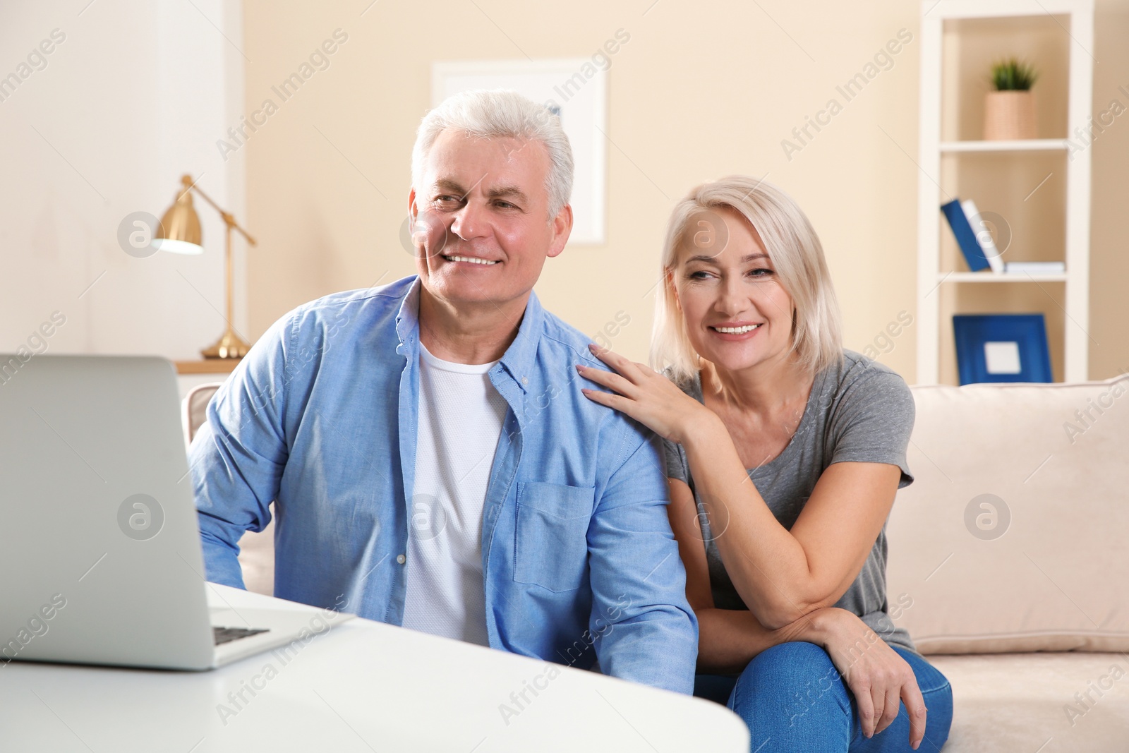 Photo of Mature couple using video chat on laptop at home