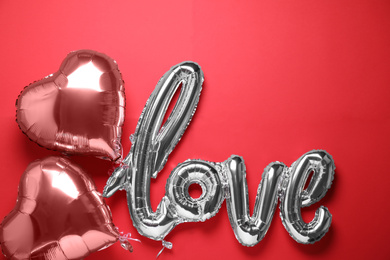 LOVE word and heart balloons on red background, flat lay