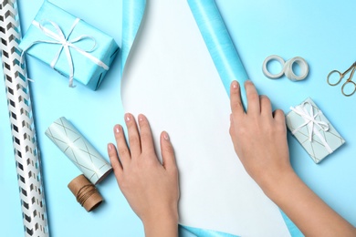 Woman decorating gift box on color background, top view