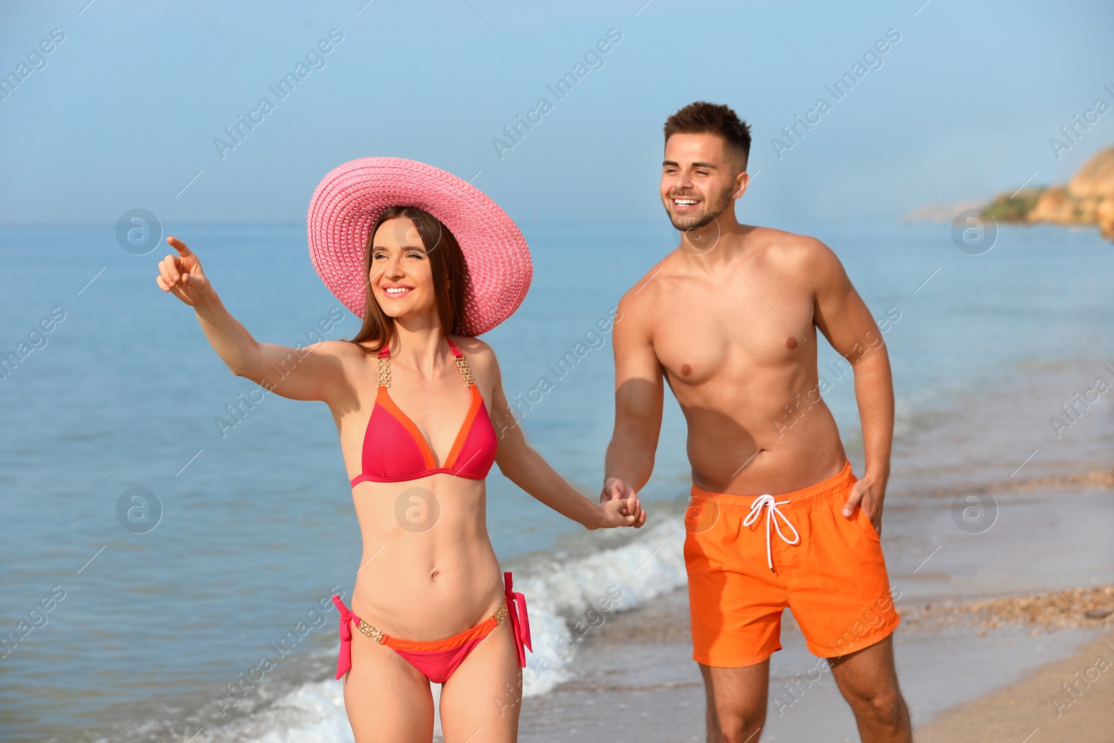 Photo of Young woman in bikini with her boyfriend on beach. Lovely couple