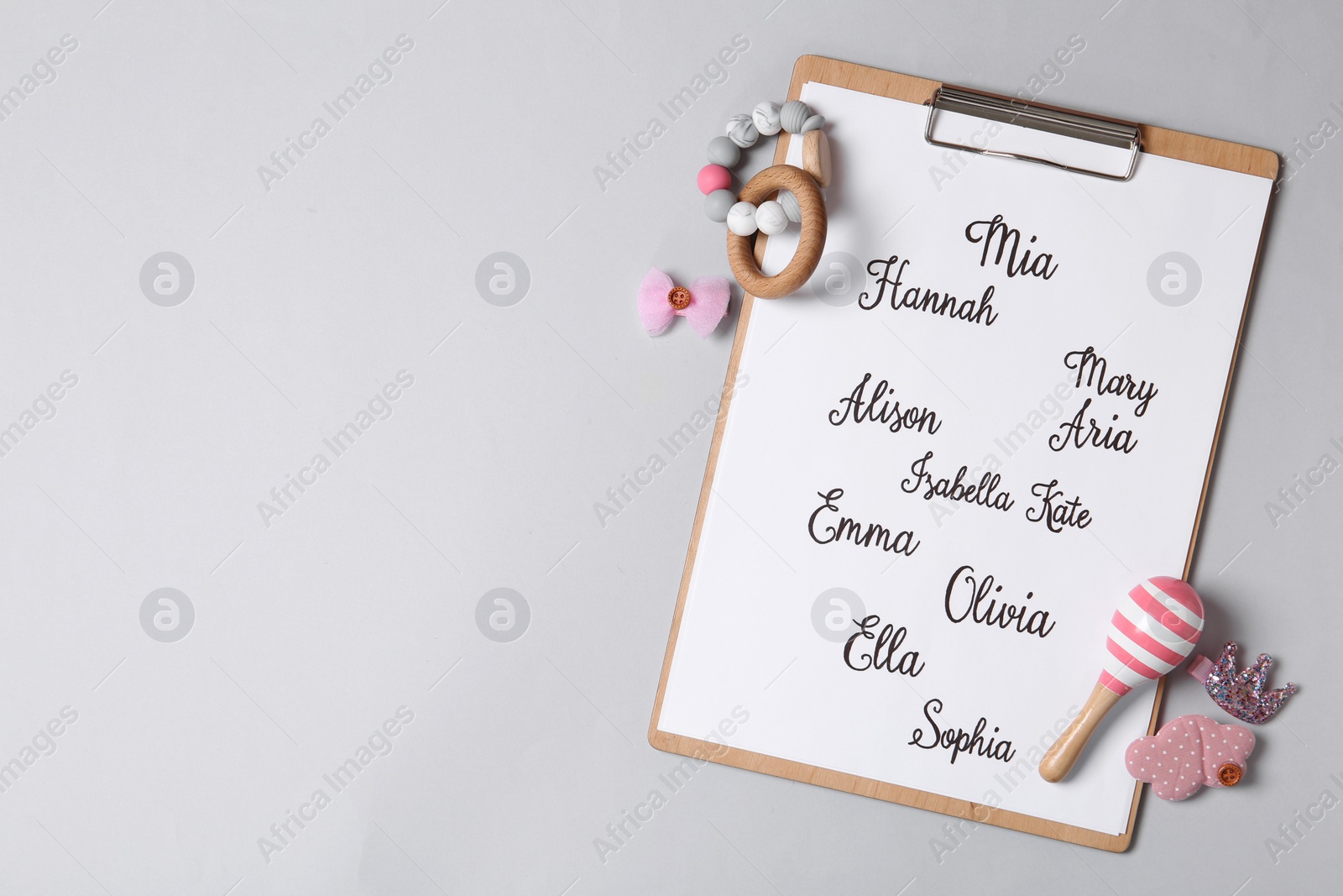 Photo of Clipboard with different baby names and toys on grey background, top view. Space for text
