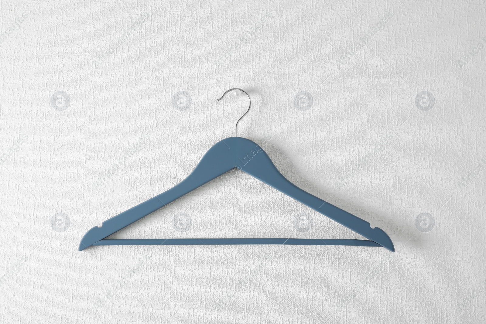 Photo of Empty clothes hanger on light wall. Wardrobe accessory