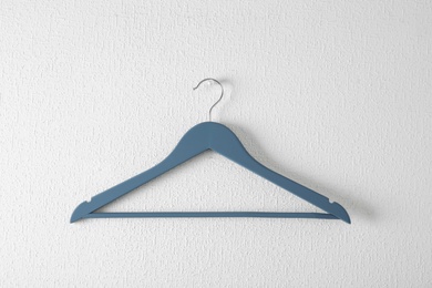 Photo of Empty clothes hanger on light wall. Wardrobe accessory