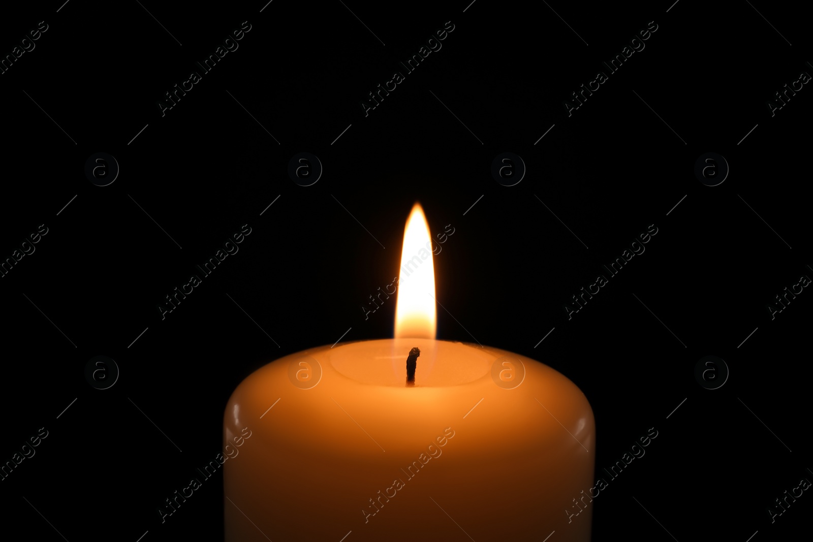 Photo of Wax candle burning on black background, closeup