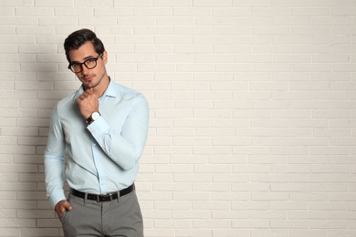 Photo of Young man with glasses near brick wall. Space for text