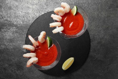 Tasty shrimp cocktail with sauce in glasses and lime on grey table, flat lay