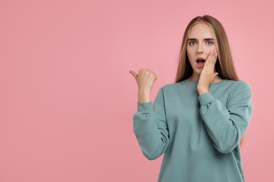 Photo of Special promotion. Emotional woman pointing at something on pink background, space for text
