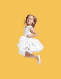 Image of Happy cute girl jumping on pale orange background