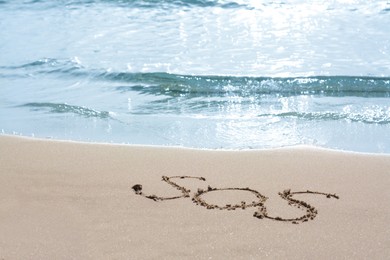 Photo of Message SOS drawn on sandy beach near sea