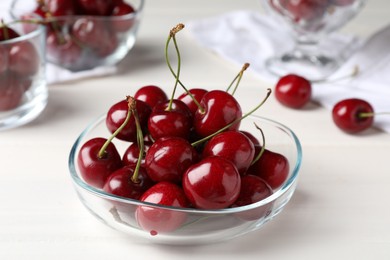 Photo of Sweet red cherries in bowl on white wooden table, closeup