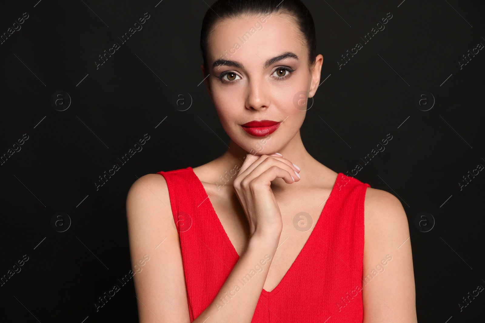 Photo of Portrait of young woman wearing beautiful red lipstick on black background