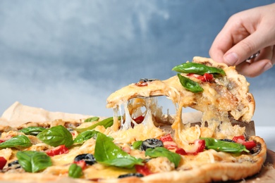 Photo of Woman taking delicious homemade pizza slice with melted cheese, closeup
