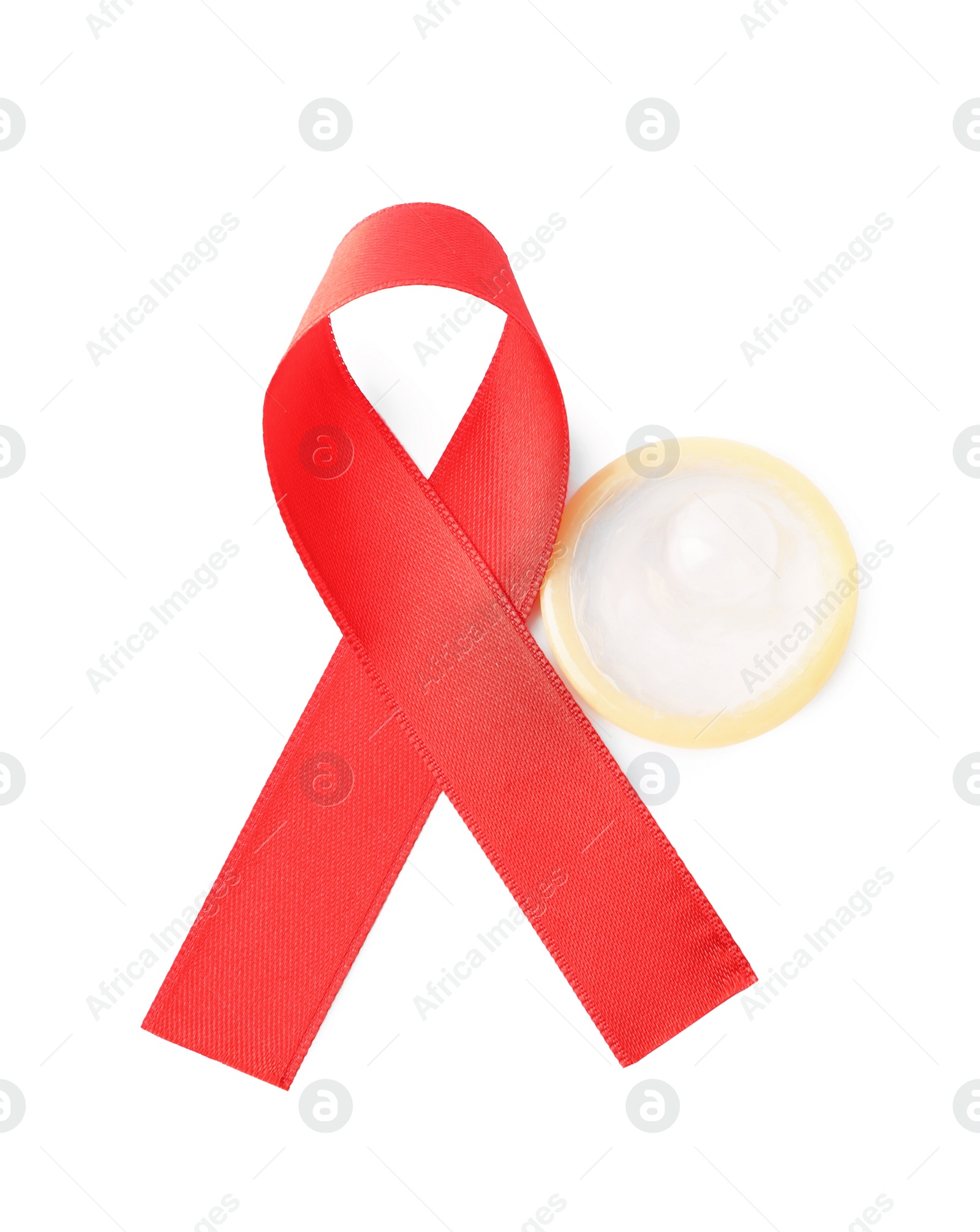 Photo of Red ribbon and condom isolated on white, above view. AIDS disease awareness