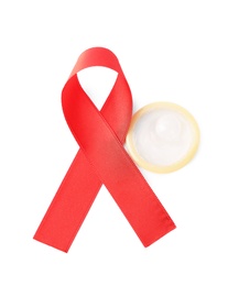 Photo of Red ribbon and condom isolated on white, above view. AIDS disease awareness