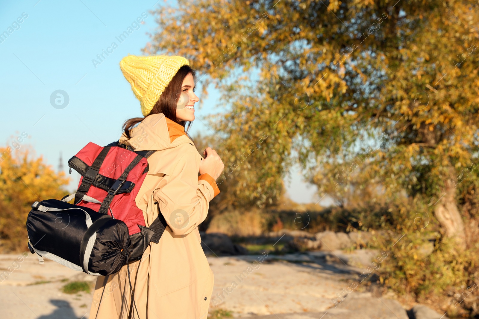 Photo of Female camper with backpack and sleeping bag in wilderness. Space for text